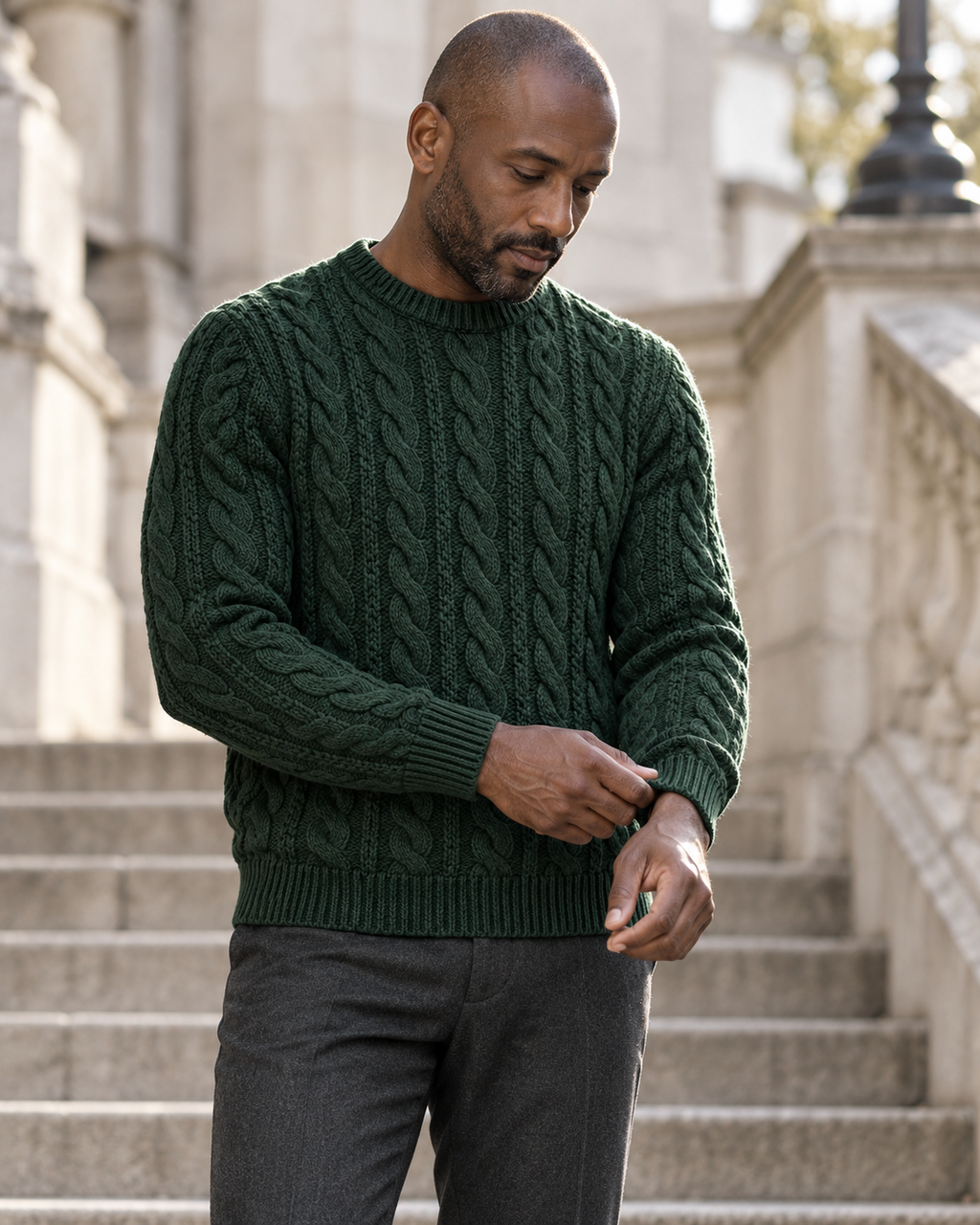 Man adjusting the cuff of Cable Knit Jumper Timeless Refined on stone steps